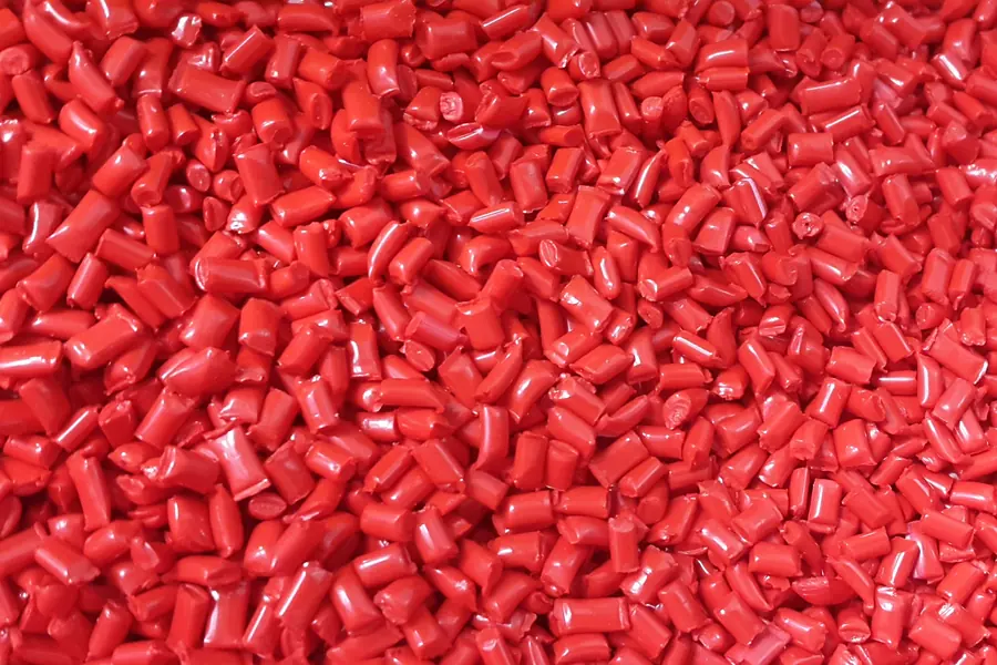 Granza de polímero roja, materia prima del proceso de inyección